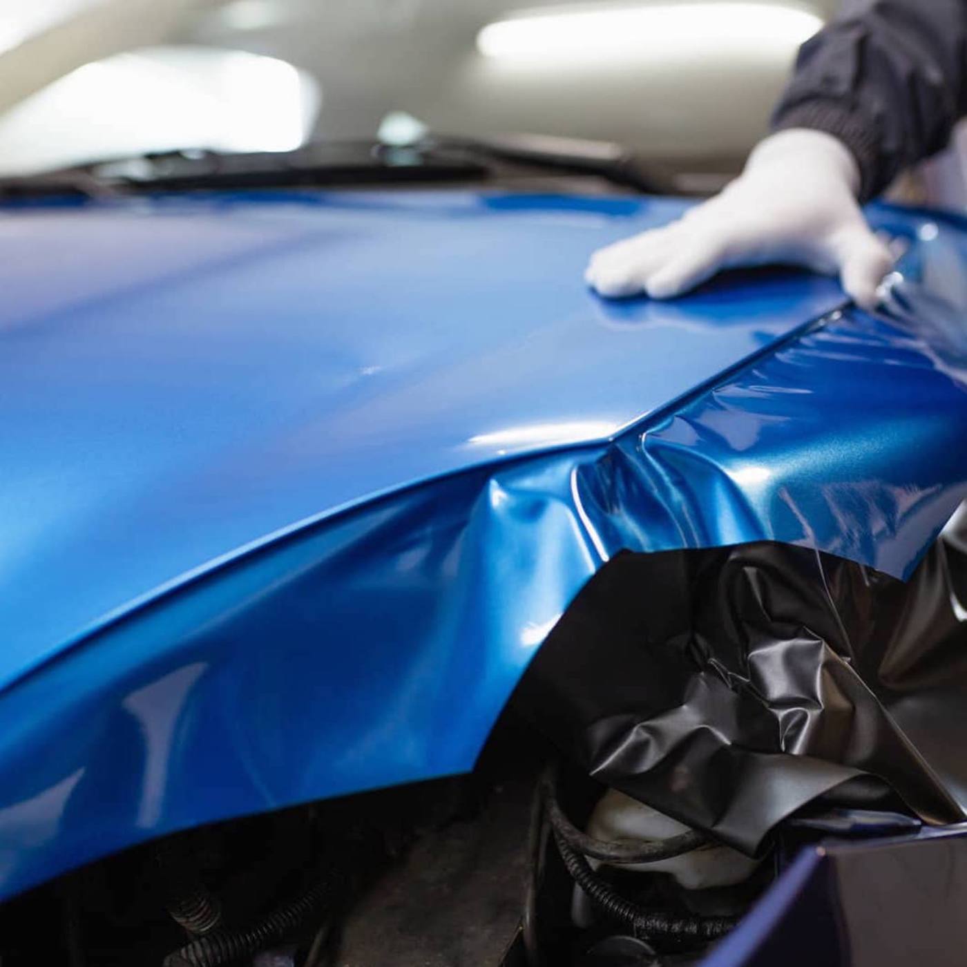 Satin blue vinyl wrap being applied to a fender